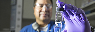 Man in lab looking at glass vial